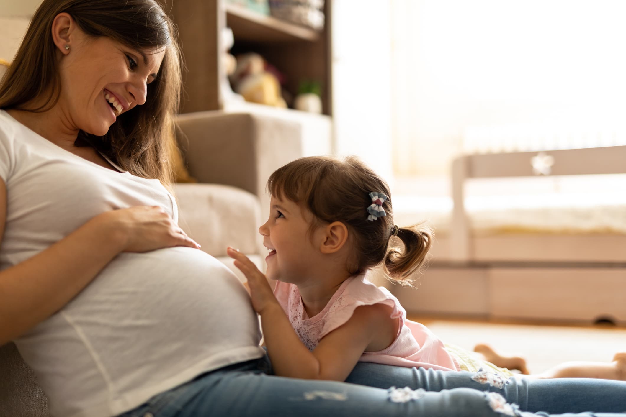 Pregnant woman in warm red, hands resting on belly